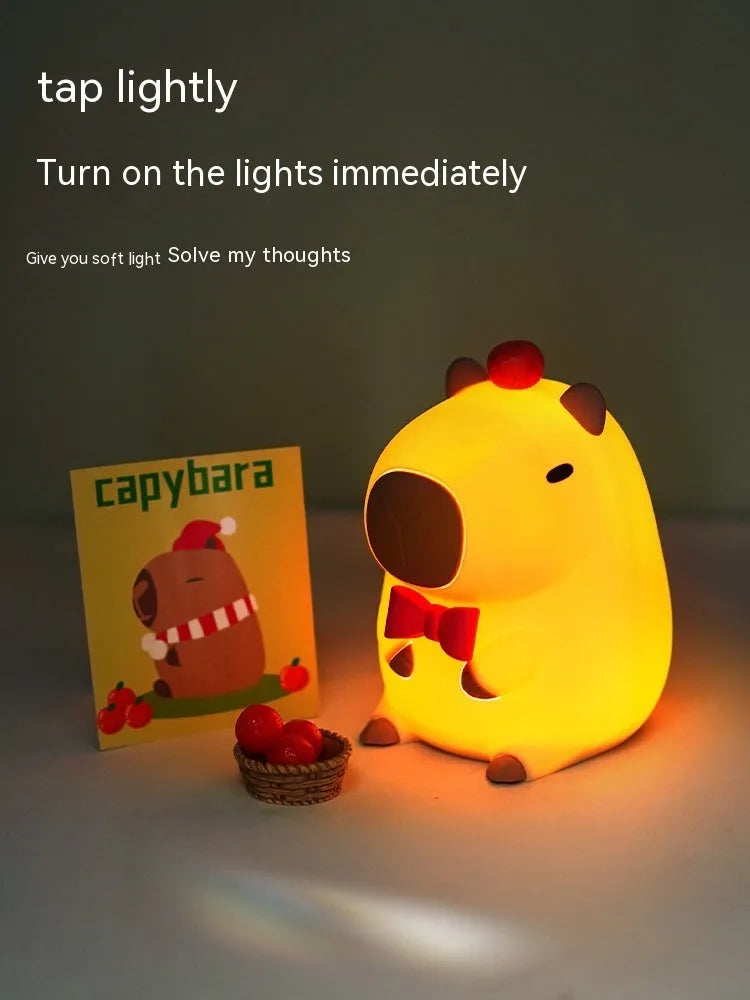 Small capybara-shaped night lamp in silicone and plastic, shown with USB cable.