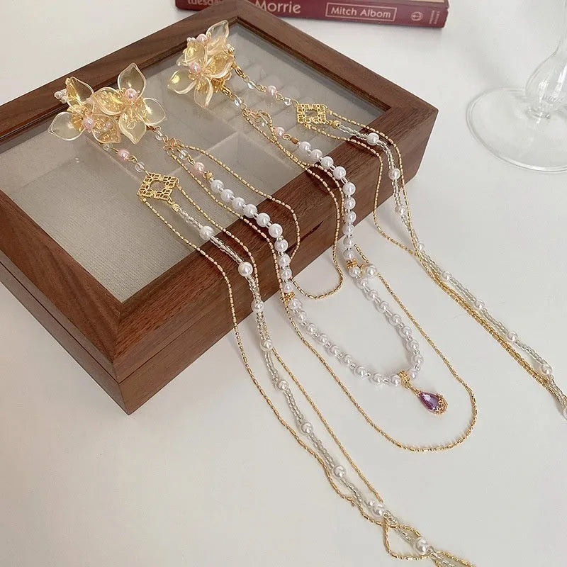 Women's decorative hairpin with pearl, diamond, and flower elements on long tassel with gold grip