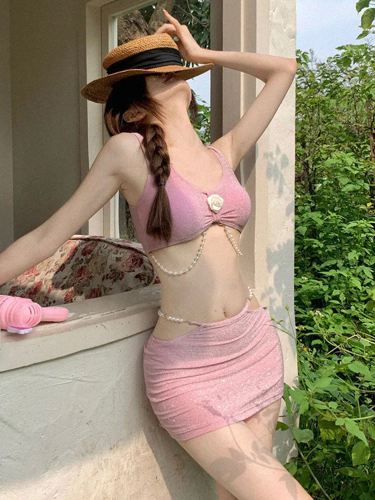 Pink and black three-piece bikini set on a hanger, showing briefs style and sleeveless design.