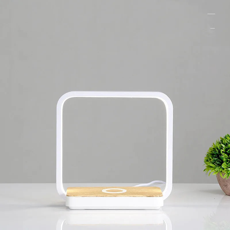 LED desk lamp with wireless charging base in round white finish on a wooden desk