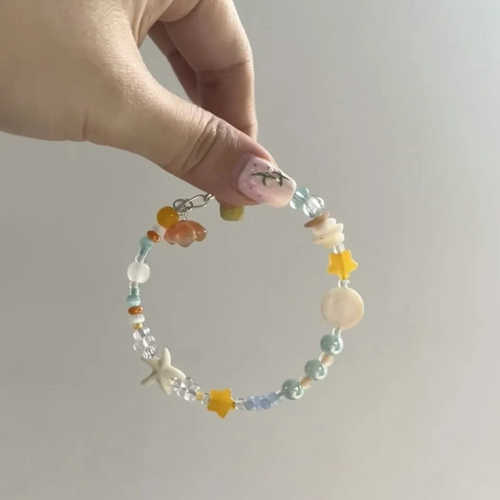 Orange mixed material women's bracelet with diamond shape and round decorative seaside elements.