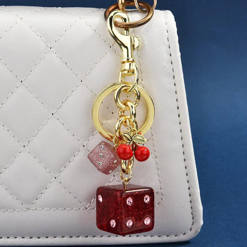 Square cherry red and silver two-tone dice keychain pendant with metal keyring on a grey background