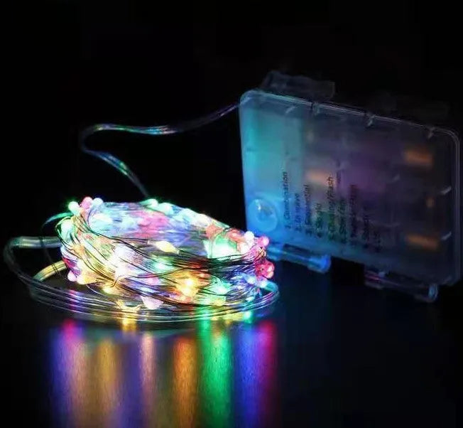 Close-up of flexible copper wire string light with 120 tiny LED bulbs, shaped in a spiral next to the battery control box.