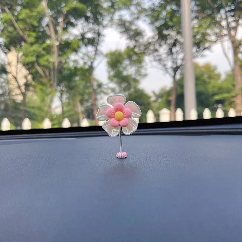 Small colourful plastic swing car decoration hanging from a rear-view mirror, showing blue, green, pink, purple, and yellow colour options.
