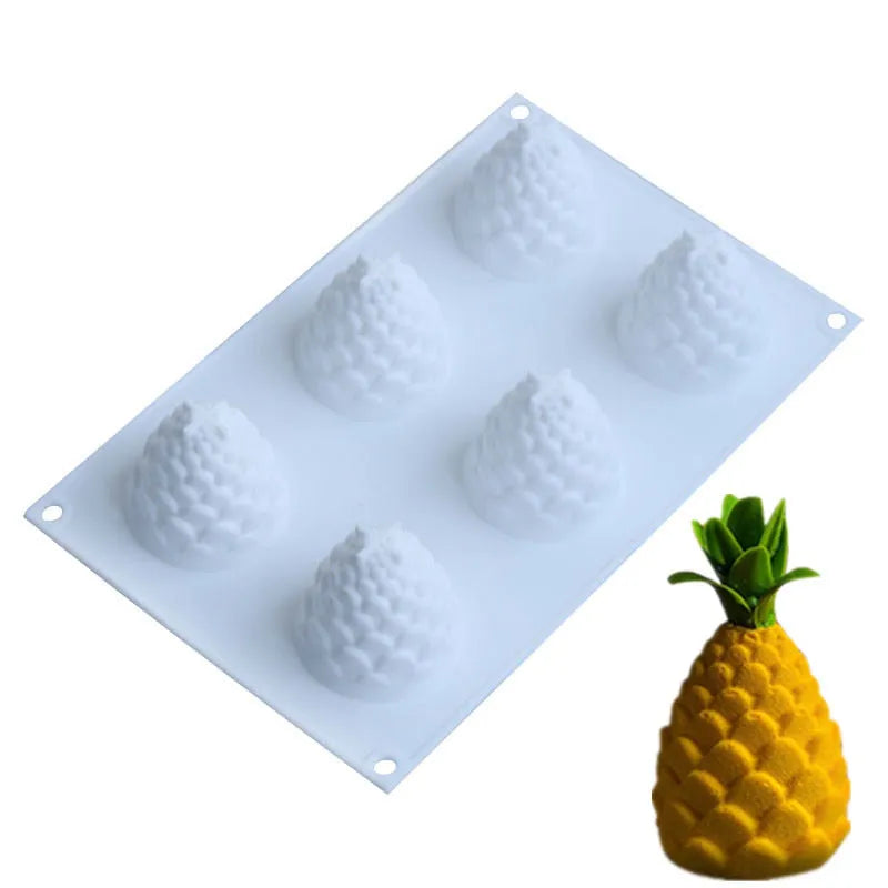 Set of six silicone baking moulds shaped as pineapples, pine cones, and pears on a kitchen counter.