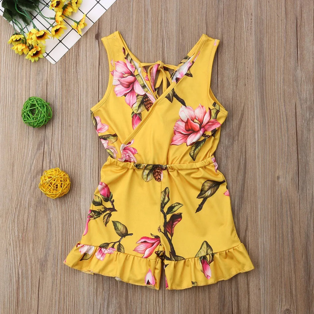 Baby girl wearing a white or yellow floral cotton summer dress.