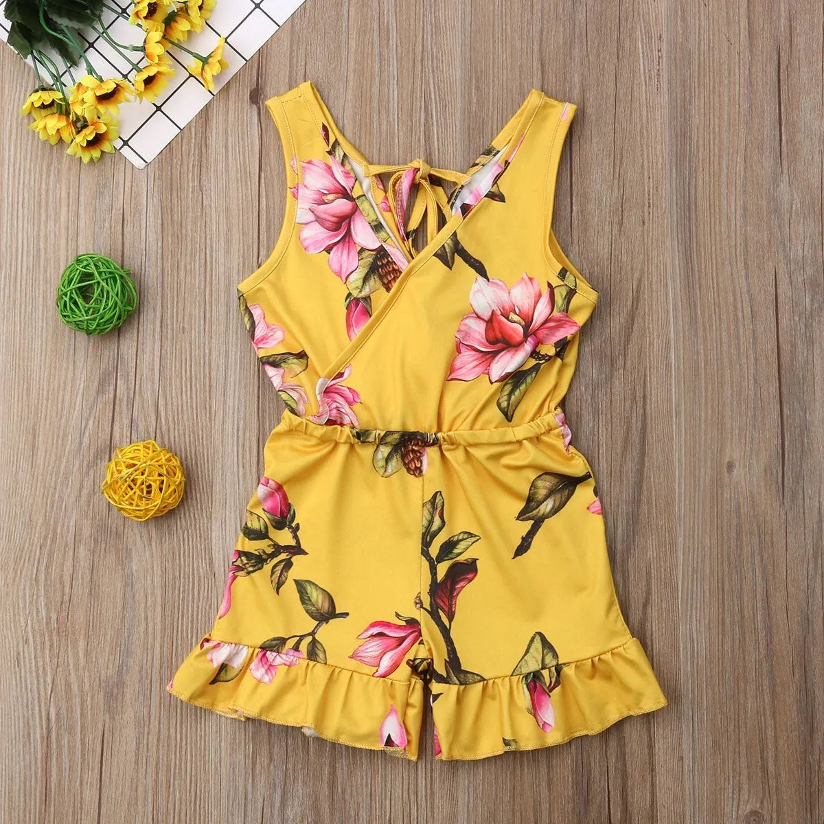 Baby girl wearing a white or yellow floral cotton summer dress.