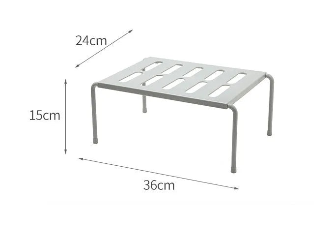 White telescopic plastic storage rack extended to full height with kitchen utensils organised on shelf