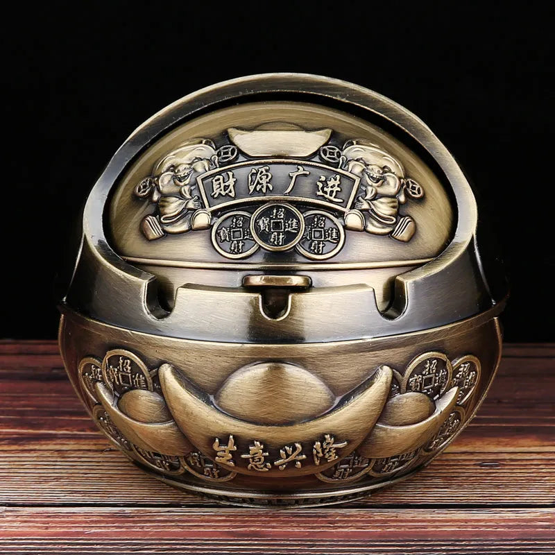 Bronze and red copper alloy decorative ashtray with smoke-extinguishing slot on a table.