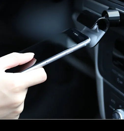Black universal car phone holder mounted on dashboard with phone inserted showing 360-degree rotation