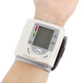 Grey portable wrist blood pressure monitor with digital display showing measurements