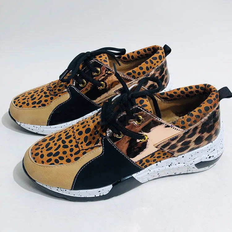 Women's black suede wedge sneakers with a round toe and low-cut design on a wooden floor.