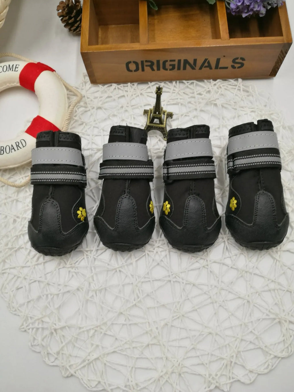 Black pet dog shoes with waterproof PVC sole and adjustable fuzzy belt on a light background