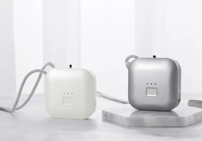 Mini USB portable air purifier necklace in pink, showing compact size and wearable design.