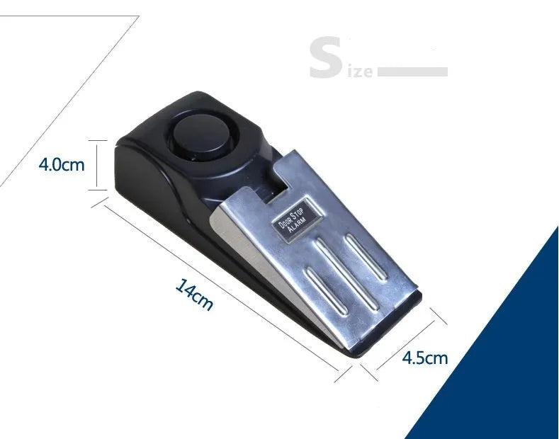 Black portable door stop alarm with wedge shape and stainless steel cover on a wooden floor.