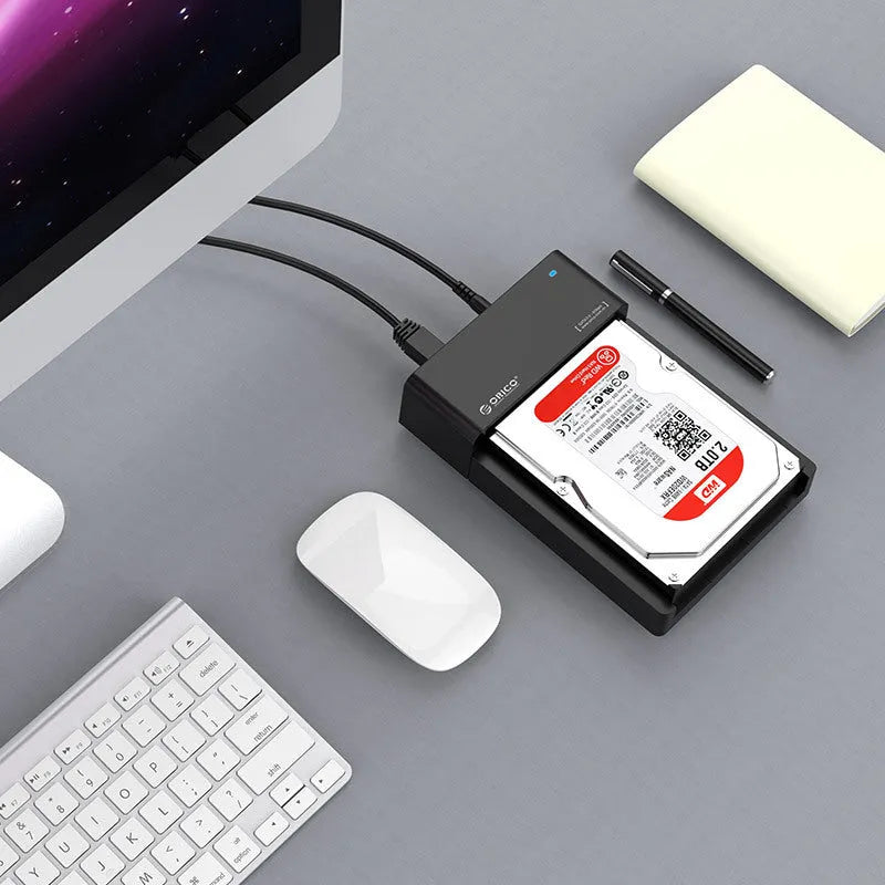 Black plastic 2.5 inch SATA hard drive enclosure with USB cable on a desk