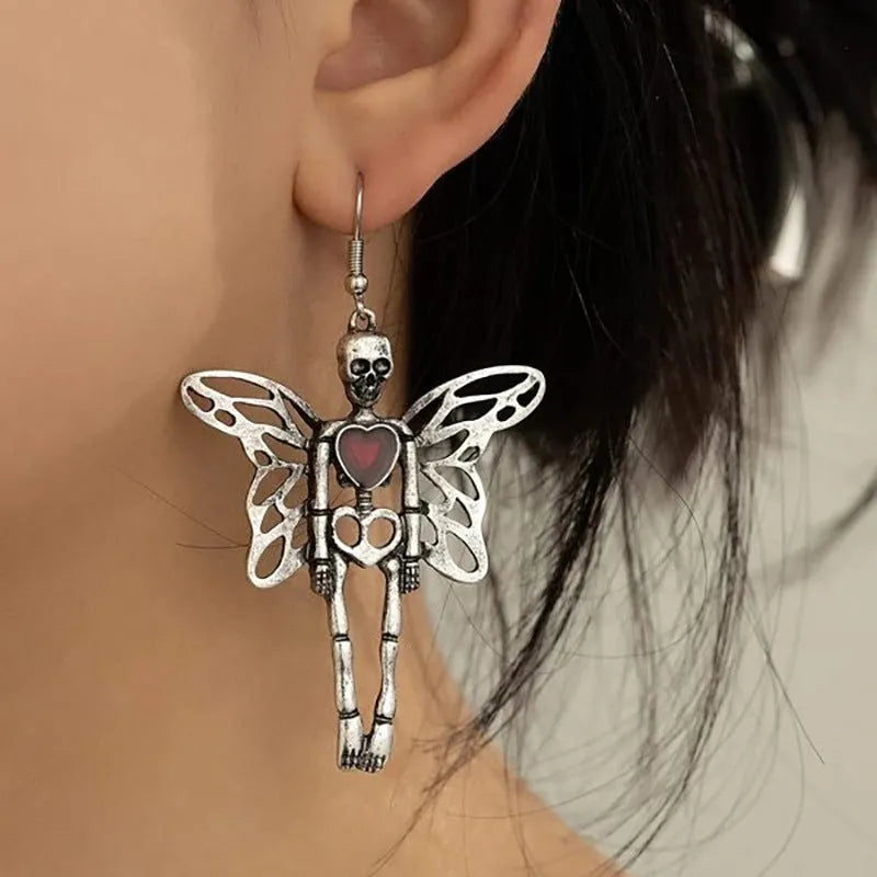 Pair of silver-coloured alloy earrings with exaggerated skull design on white background