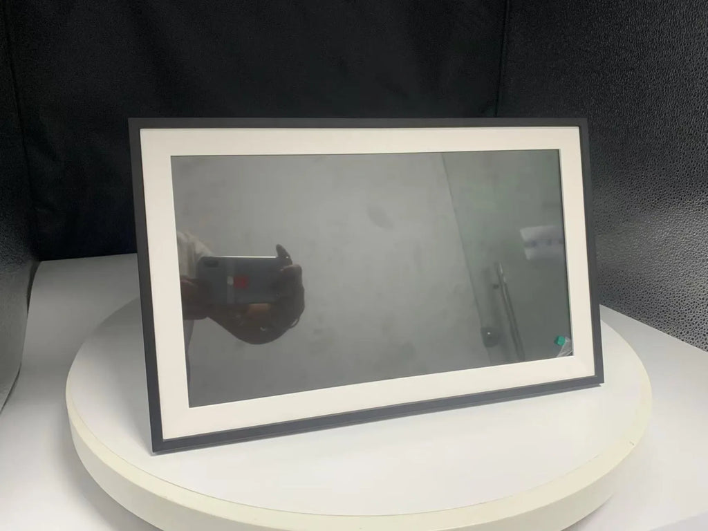 White 15.6 inch smart digital photo frame with Full HD screen on a wooden desk.