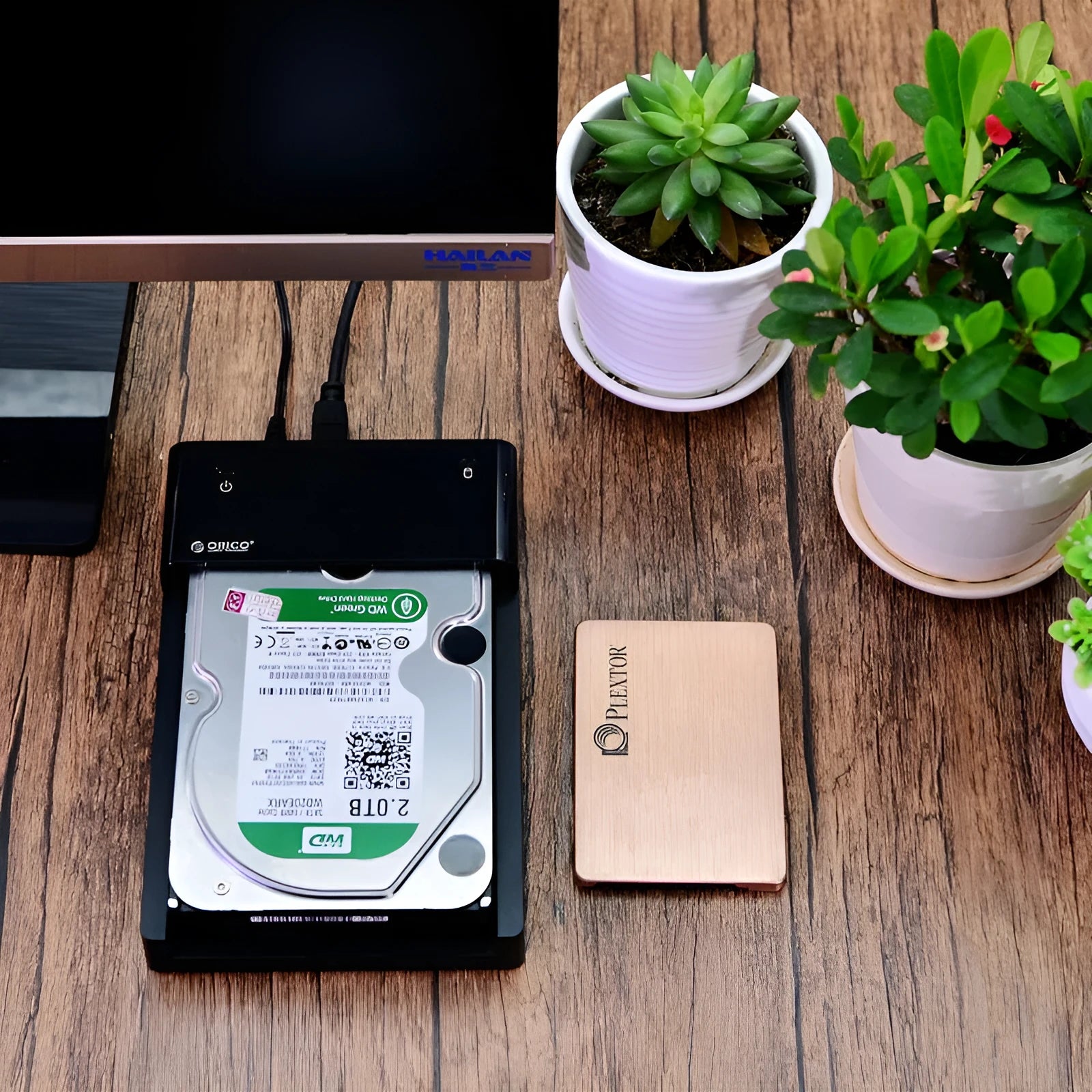 Black plastic 2.5 inch SATA hard drive enclosure with USB cable on a desk