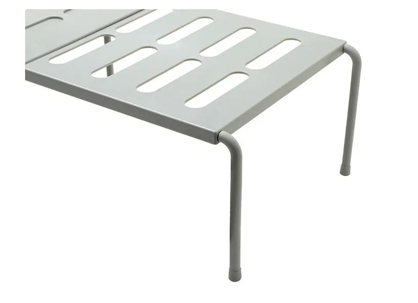 White telescopic plastic storage rack extended to full height with kitchen utensils organised on shelf