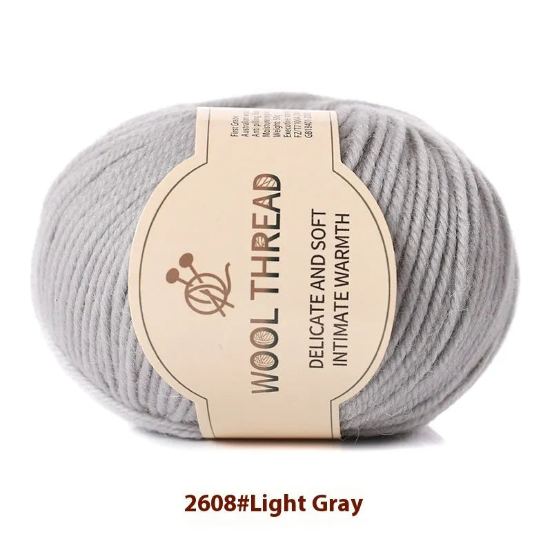 One roll of beige domestic wool hand-knitting yarn for size 10 needles next to knitting needles.