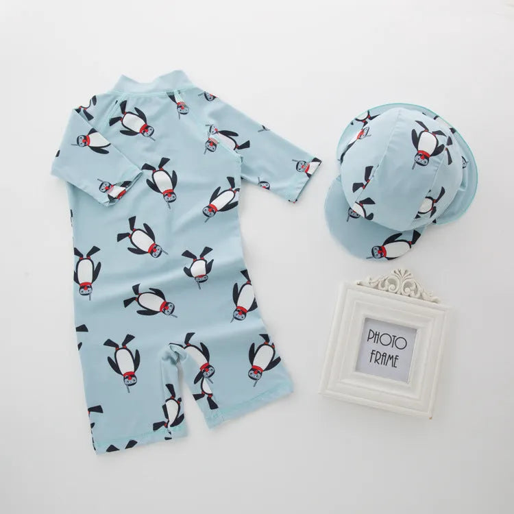 Boy's penguin print long sleeve swimsuit top and matching swim cap set on blue background