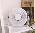 Mini black USB desk fan with adjustable head on a desk next to a laptop.