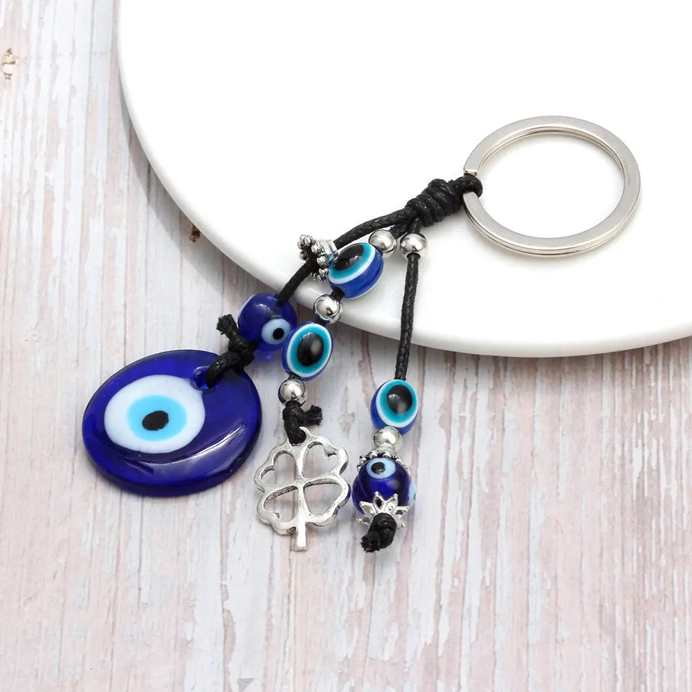 Blue metal eye of evil keychain 4cm pendant with plant-inspired design on grey background