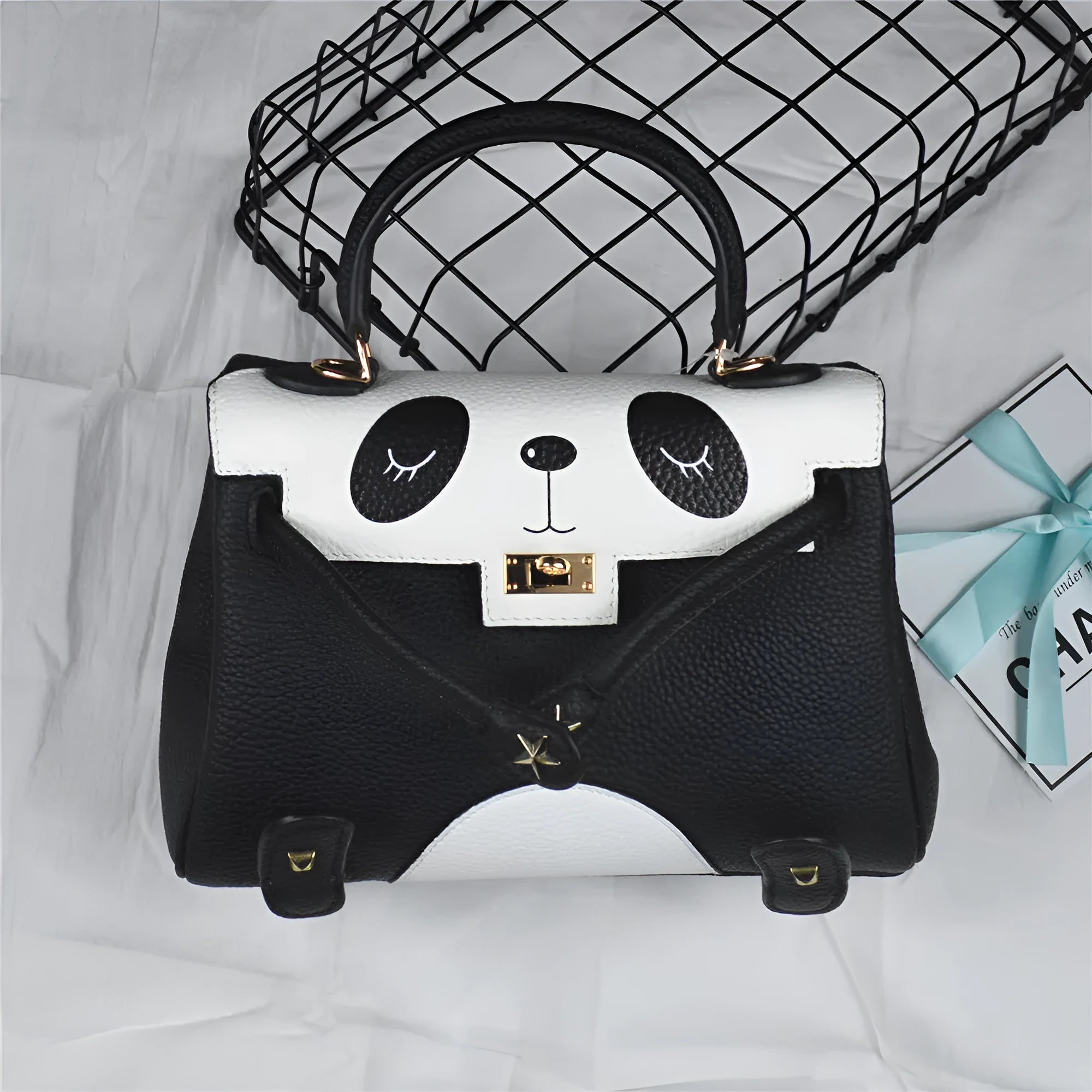 Black and white panda print on a structured horizontal square cowhide leather handbag with top handles.