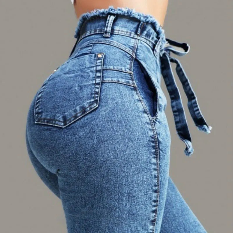 Pair of blue fringed jeans with a distressed hem laid flat, showing cowboy fabric texture.