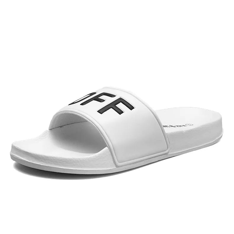 Men's black open-toe slippers with a textured rubber sole and soft viscose upper, shown on a wooden floor.
