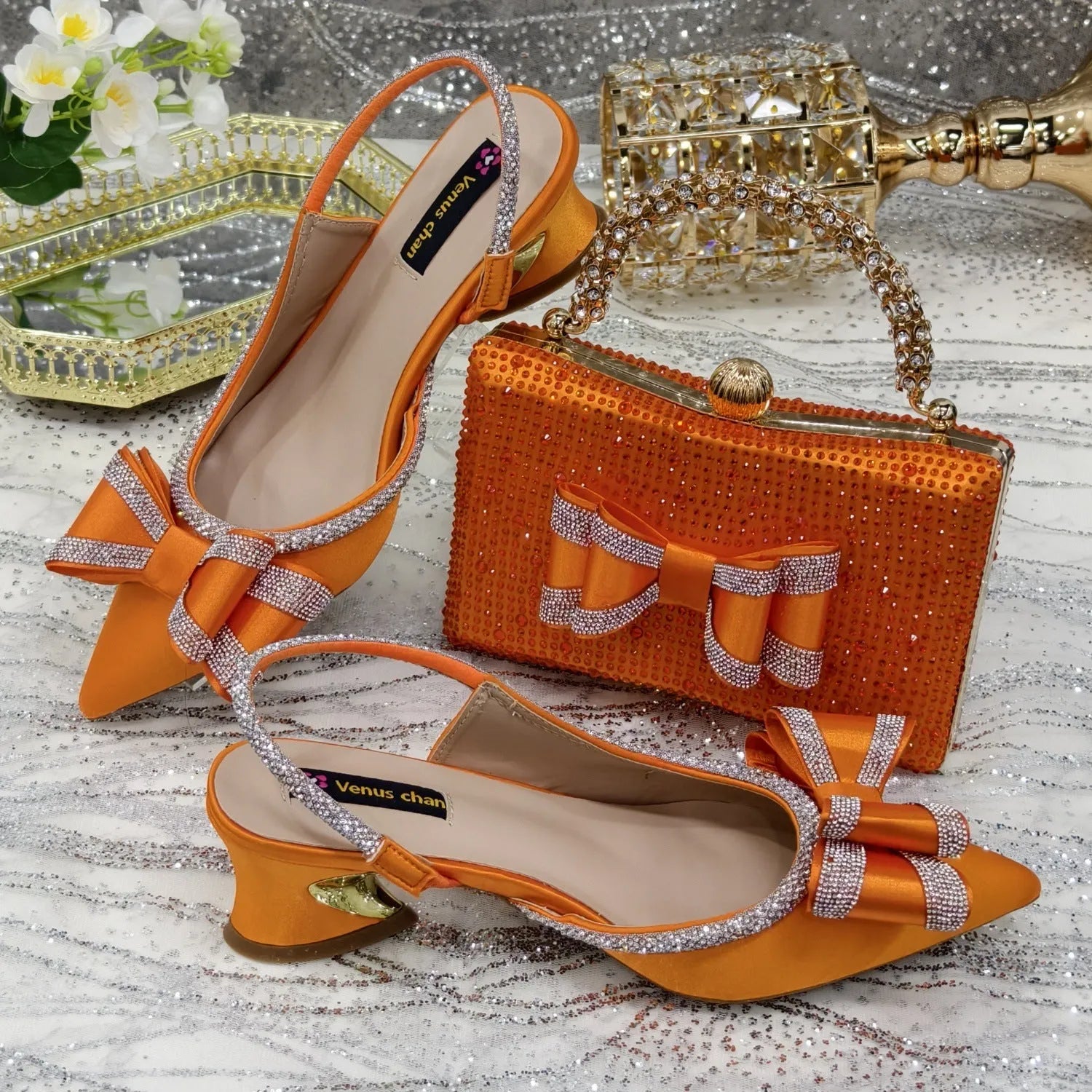 Women's black pointed toe sandals with square buckle and matching rhinestone bag on a mid-height wine glass heel.