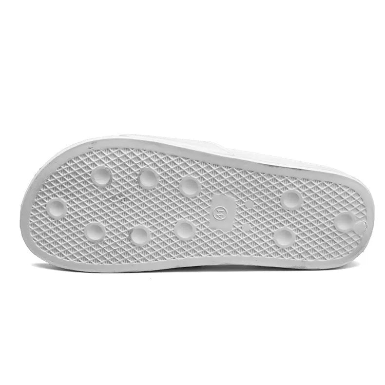Men's black open-toe slippers with a textured rubber sole and soft viscose upper, shown on a wooden floor.