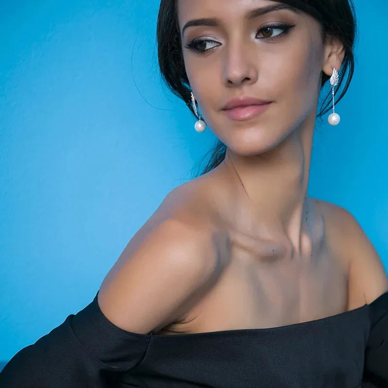 Sterling silver angel wing drop earrings with gold-plated stone inlay and diamond-cut texture.