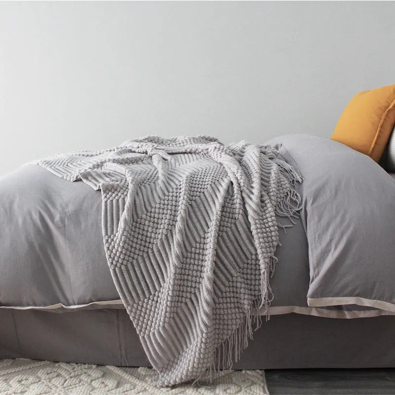 Small rectangular polyester nap blanket in dark grey, khaki, and light grey colours, measuring 127 by 170 cm.
