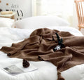 Nordic-style knit blanket with fringe trim in a neutral colour on a sofa