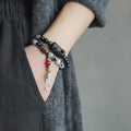 Ethnic black hair bracelet with white crystal tassel, shown in boys and girls size options.