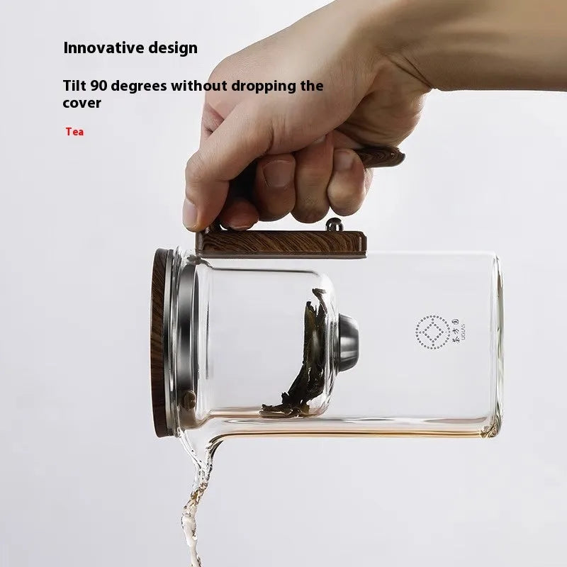 Glass teapot with wooden handle showing magnetic tea separation button and drip-free spout.
