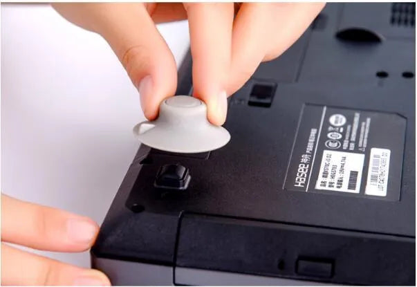Four grey plastic laptop cooling pads, two large and two small, placed under a silver laptop on a wooden desk.