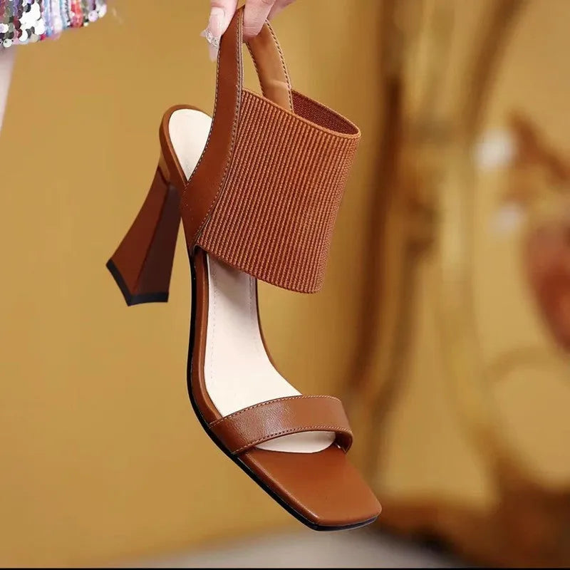 Women's black high heel sandals with a thin elastic ankle strap and a rubber sole.