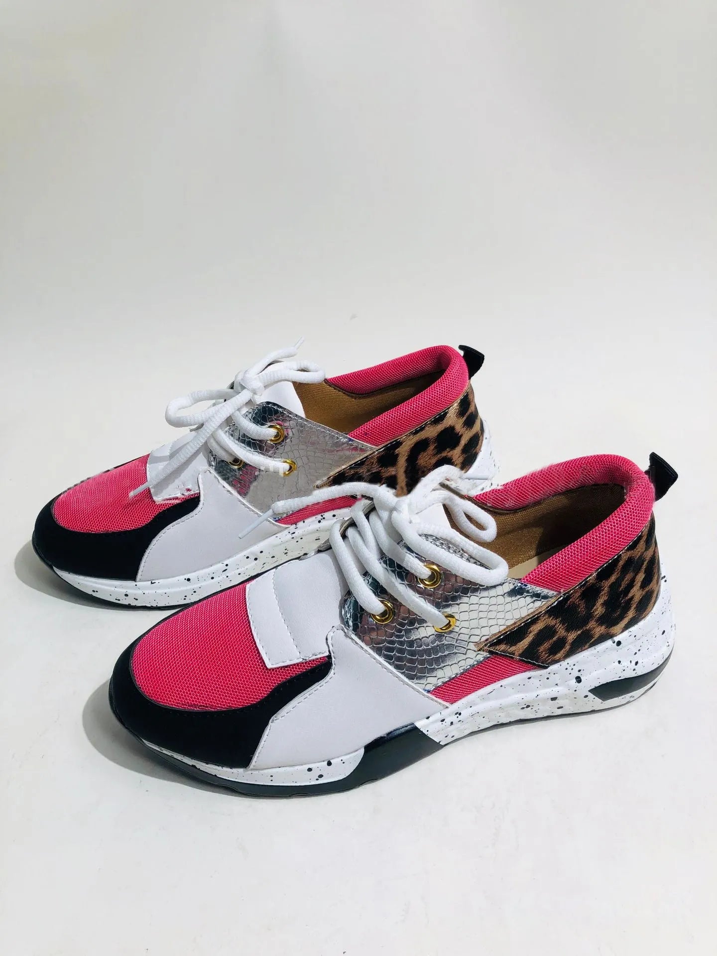 Women's black suede wedge sneakers with a round toe and low-cut design on a wooden floor.