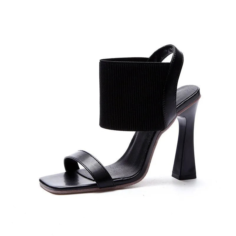 Women's black high heel sandals with a thin elastic ankle strap and a rubber sole.