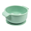 Flexible silicone pet bowl with suction cup base, shown in blue, folded flat next to a dog