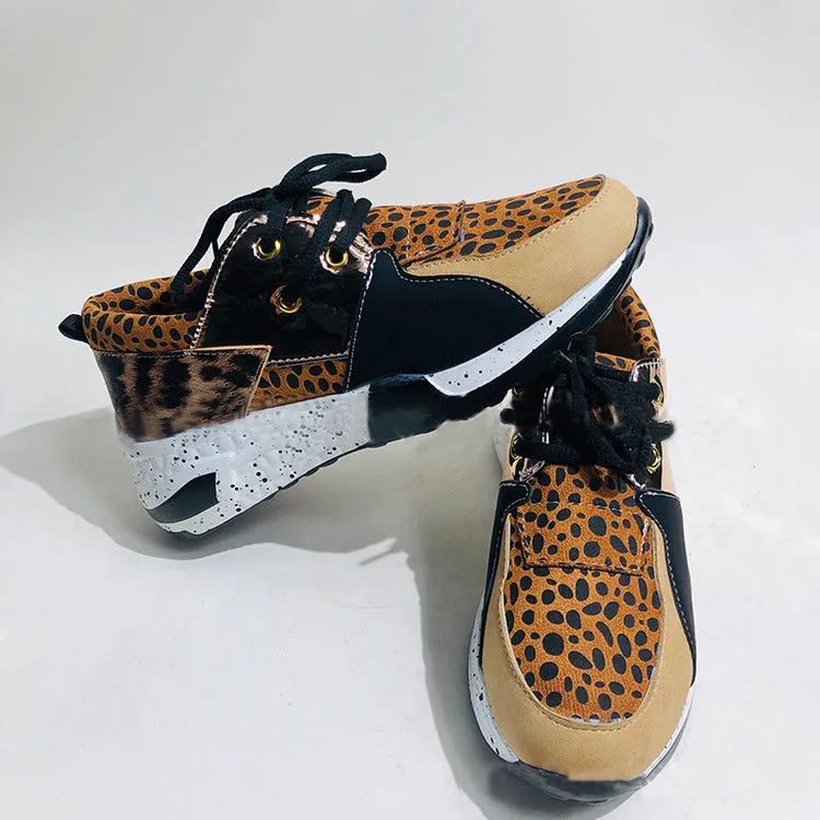 Women's black suede wedge sneakers with a round toe and low-cut design on a wooden floor.