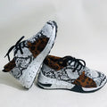 Women's black suede wedge sneakers with a round toe and low-cut design on a wooden floor.