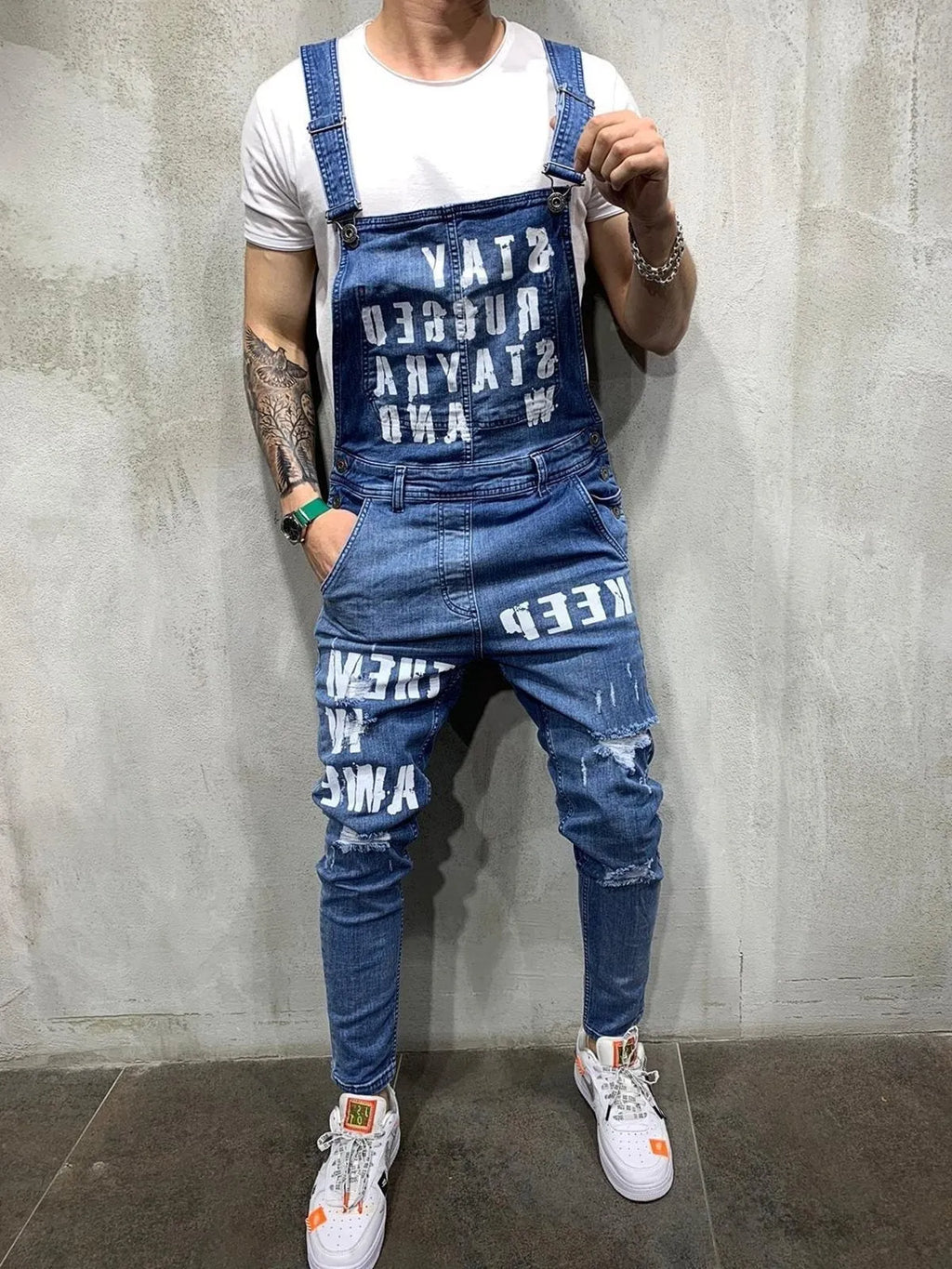 Men's black braces ripped jeans jumpsuit with adjustable shoulder straps on a model