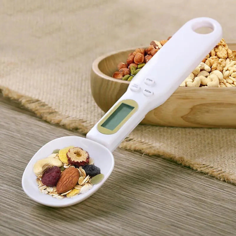 White digital spoon kitchen scale with LCD screen showing weight measurement.
