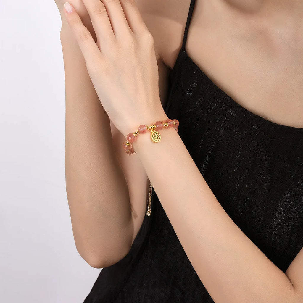Women's Strawberry Quartz crystal bracelet with geometric design and fu character charm on wrist