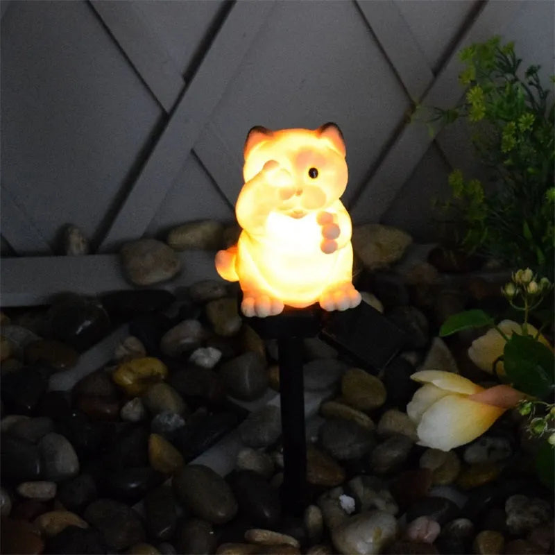 Brown cat-shaped solar lawn light with LED, placed in a garden.