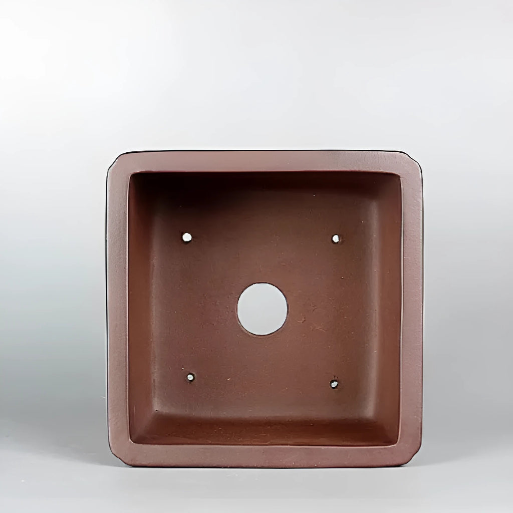 Handmade brown antique style purple clay flower pot on a windowsill.